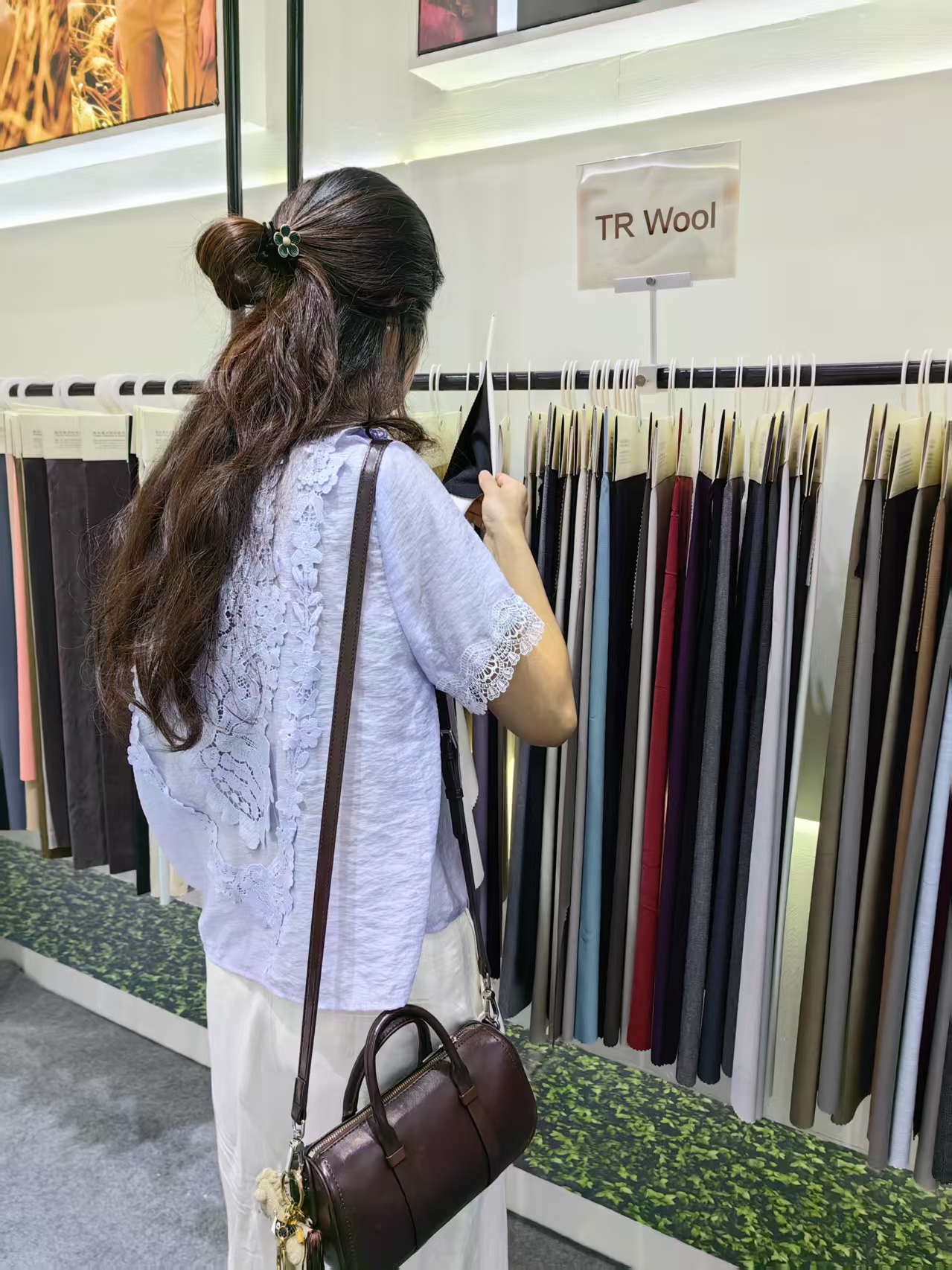 Visitor browsing fabric rolls at the Fuxing Textile booth