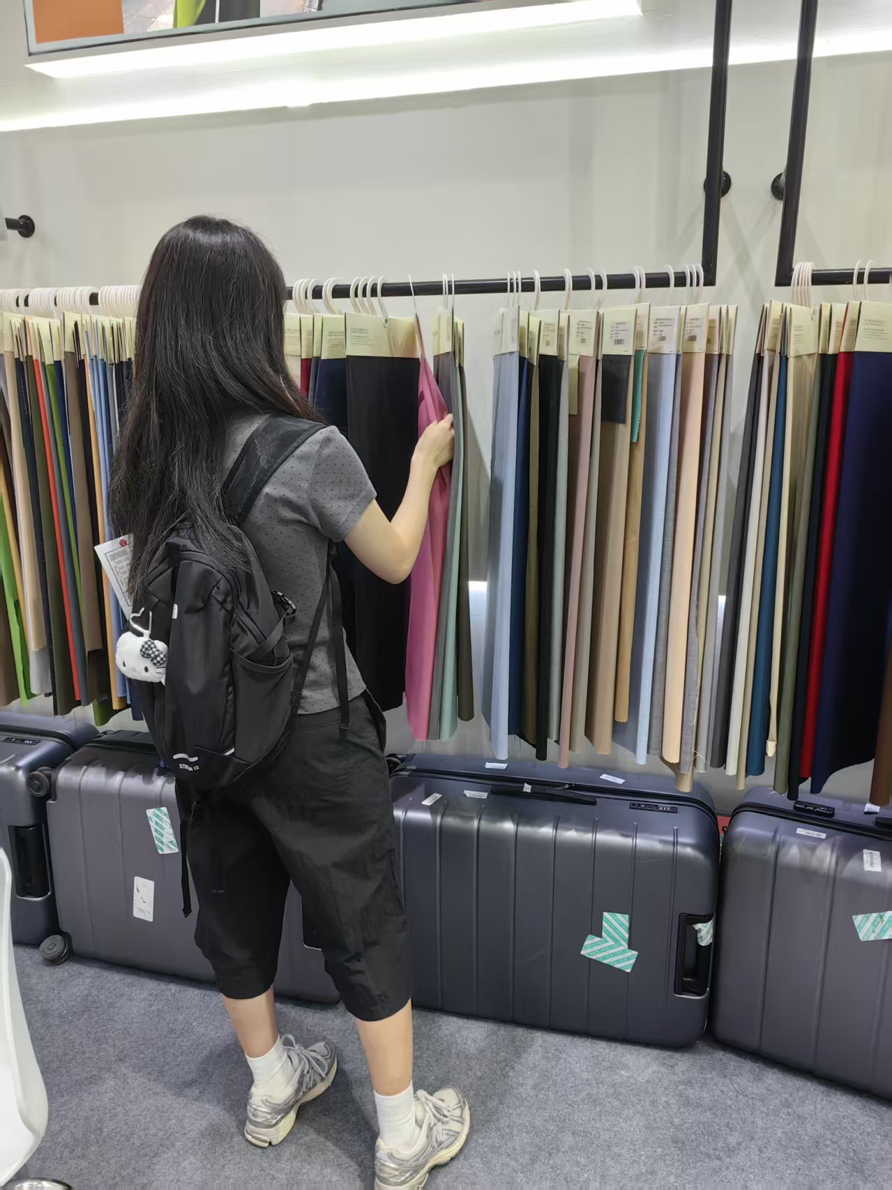 Visitor with backpack browsing the fabric rack