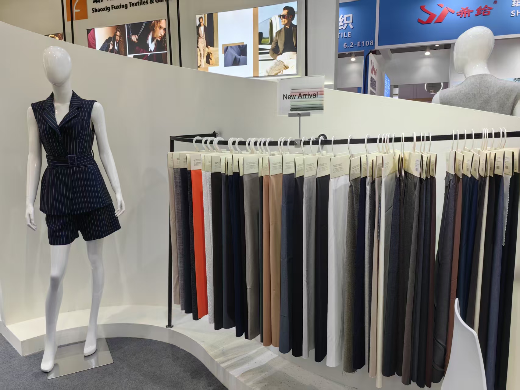 Mannequins in finished coats against the branded wall